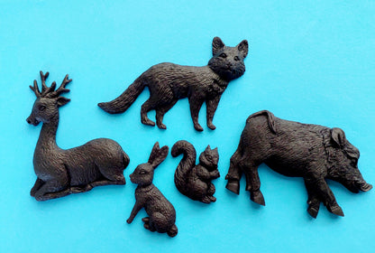 A set of five black edible cake decorations. Woodland animals, including a boar, deer, fox, rabbit, and squirrel.