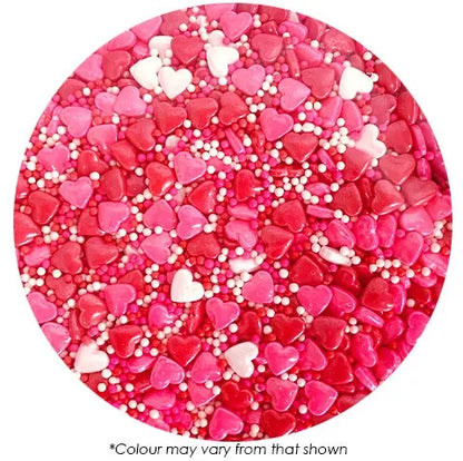 Pink heart-shaped cake sprinkles with white beads on a white background